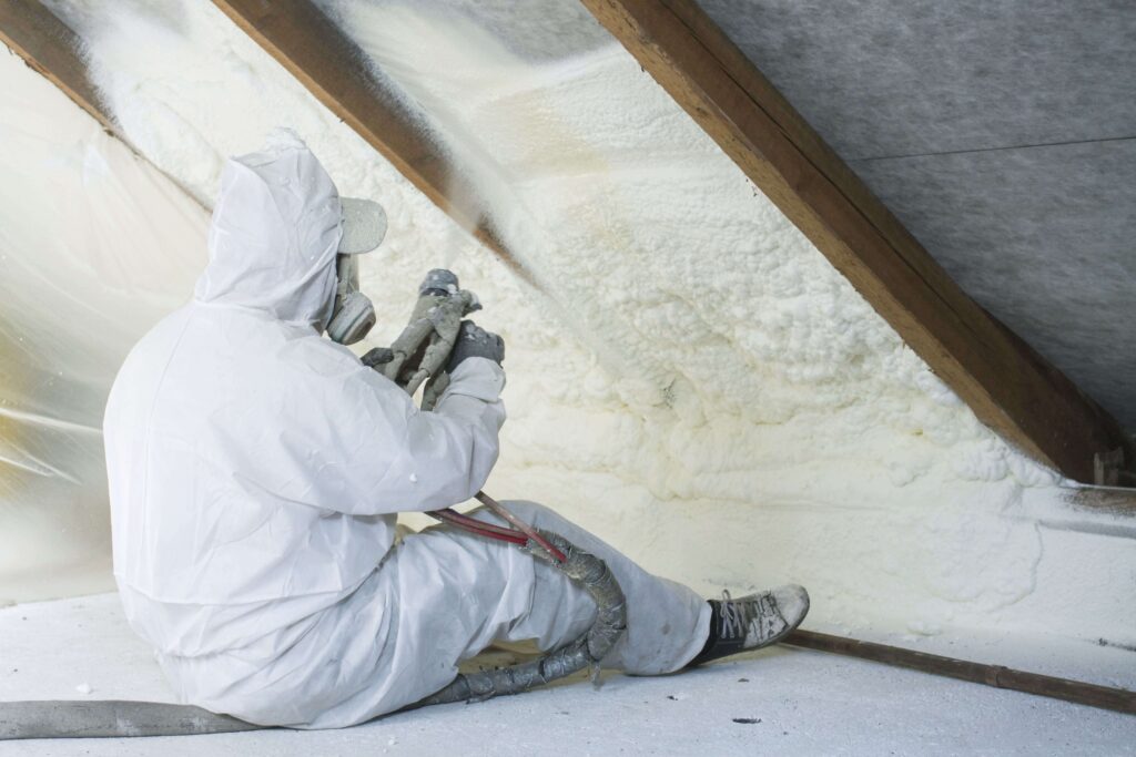 Man spraying foam insulation to residential attic