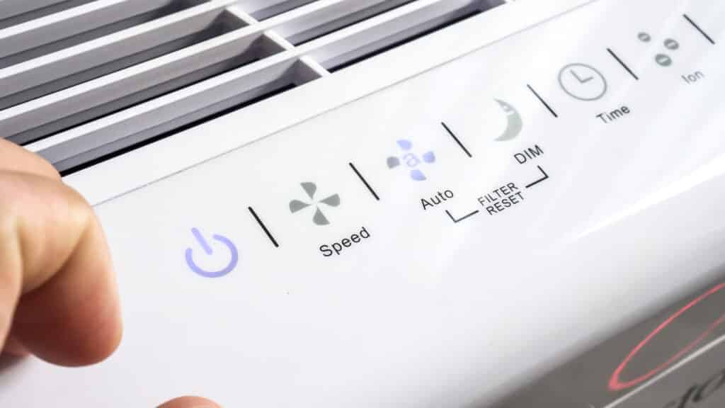 fingers beside air purifier control buttons