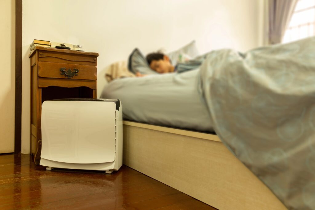 A boy sleeping comfortably in a bedroom with an air purifier | benefits of air purifier