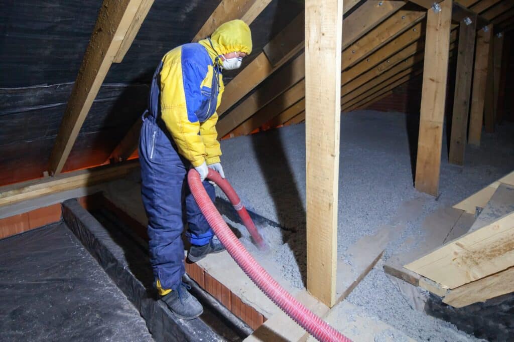 man wearing PPE while removing attic insulation